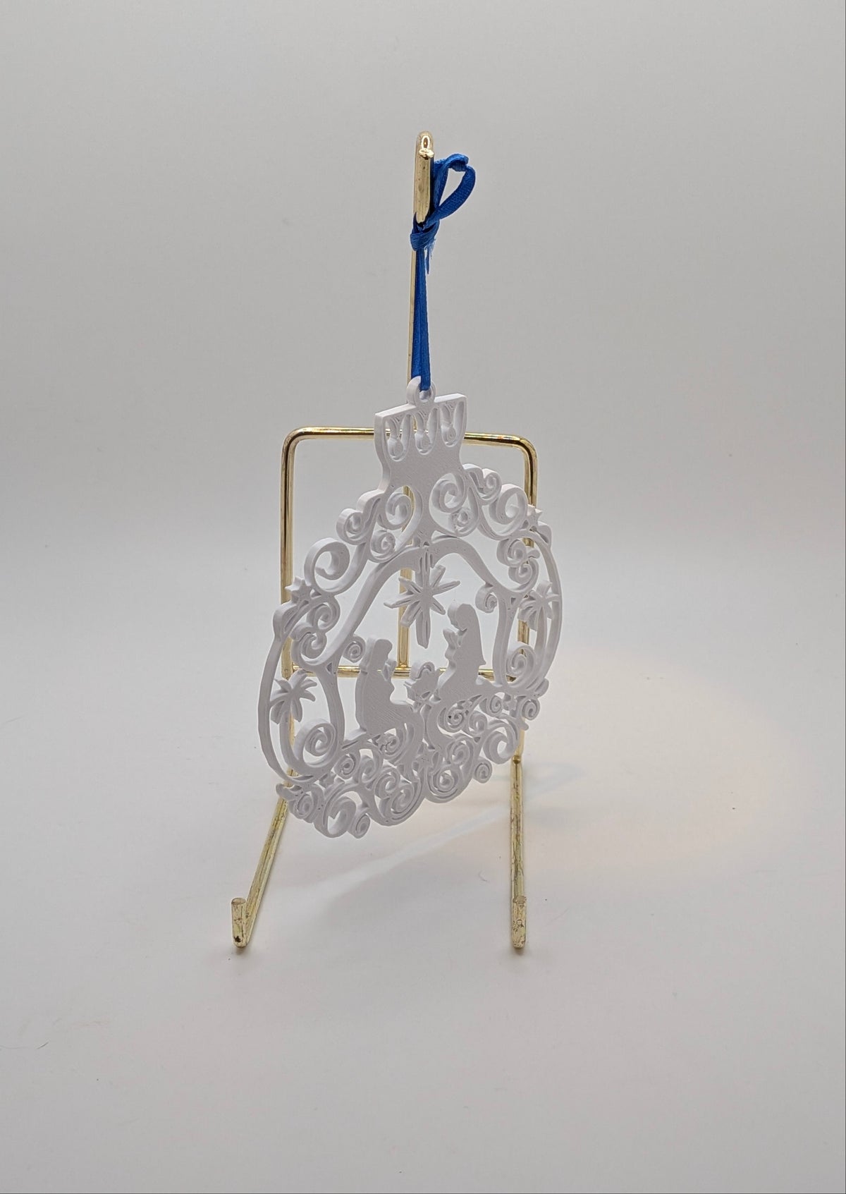 white flat manger ornament on a stand against a white background