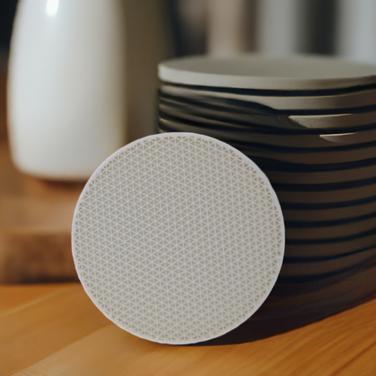 AI generated image of a white triangle pattern infill coaster on a light wood surface in front of a stack of coasters