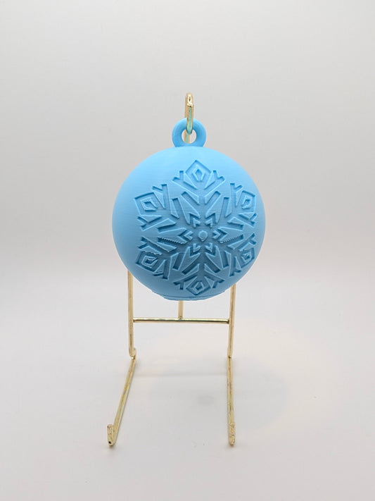 aqua bauble with snowflake pattern on a stand against a white background