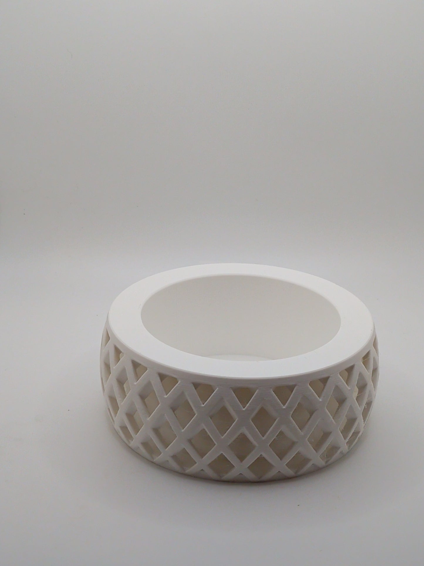 White ceramic planter with lattice design on a light gray background