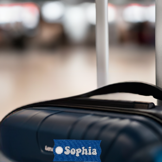 AI generated image of a blue and white small customizable name plate in front of a black suitcase