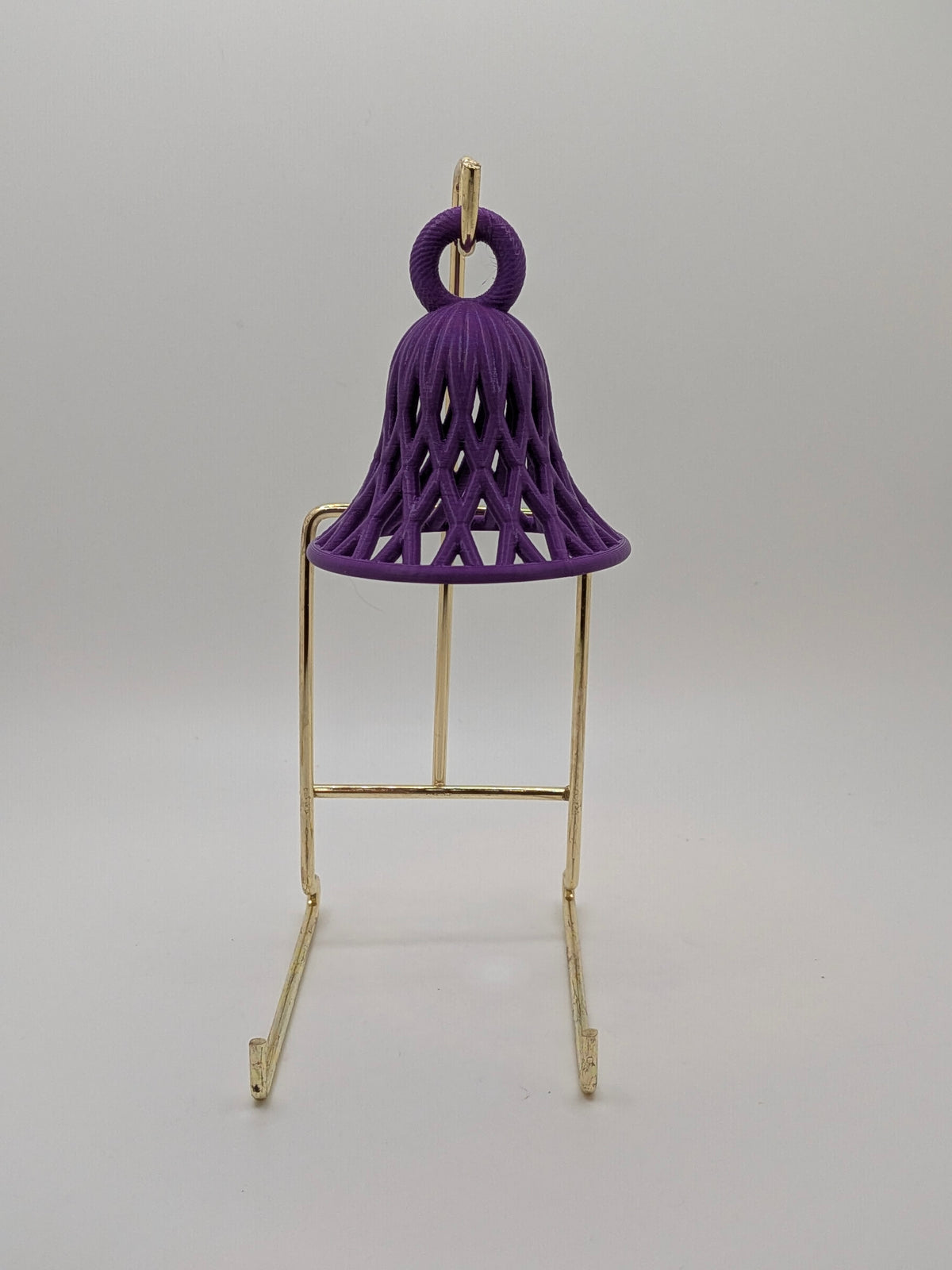 purple bell with lattice pattern ornament on a stand against a white background