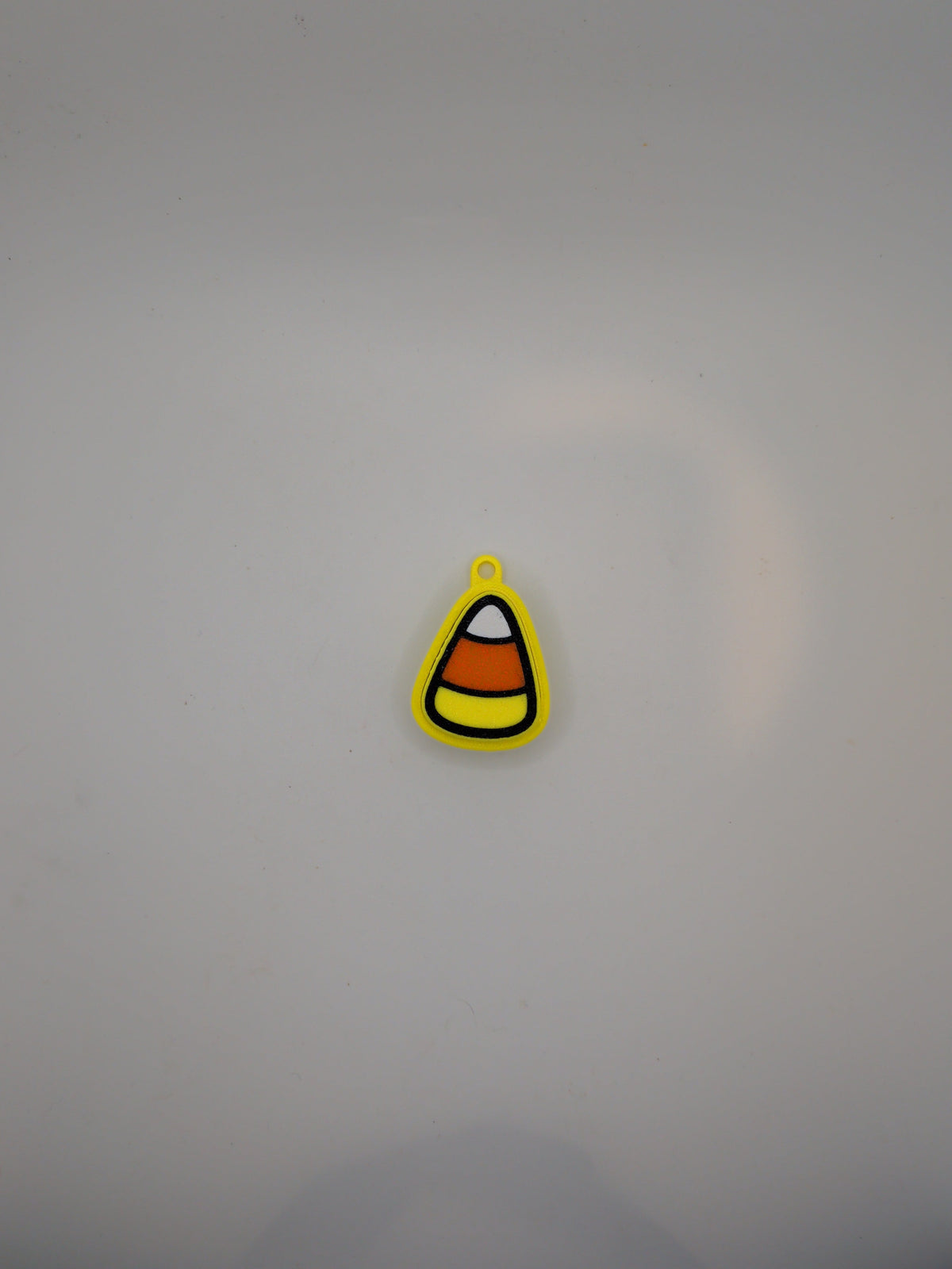 A small candy corn-shaped fidget toy with yellow, orange, white, and black stripes, shown on a plain light gray background.